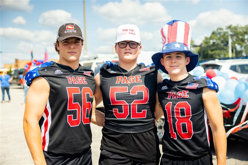 Three boys wearing football uniforms smile